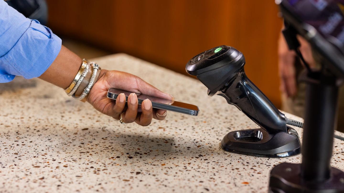 امرأة تحمل الهاتف إلى الماسح الضوئي